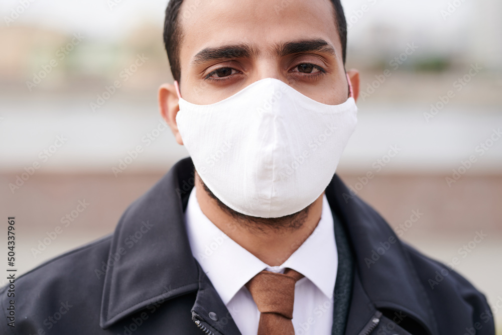 Close-up of Arabian man using mask to protect himself against coronavirus outdoors Close-up of Arabian man using mask to protect himself against coronavirus outdoors