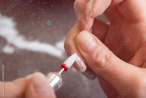 The girl removes nail polish with a special machine closeup