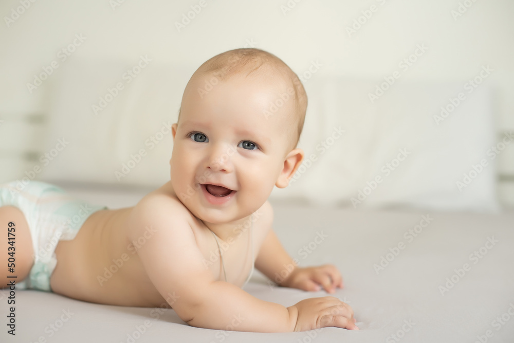 Adorable baby boy in white bedroom. Newborn child relaxing in bed. Family morning at home.