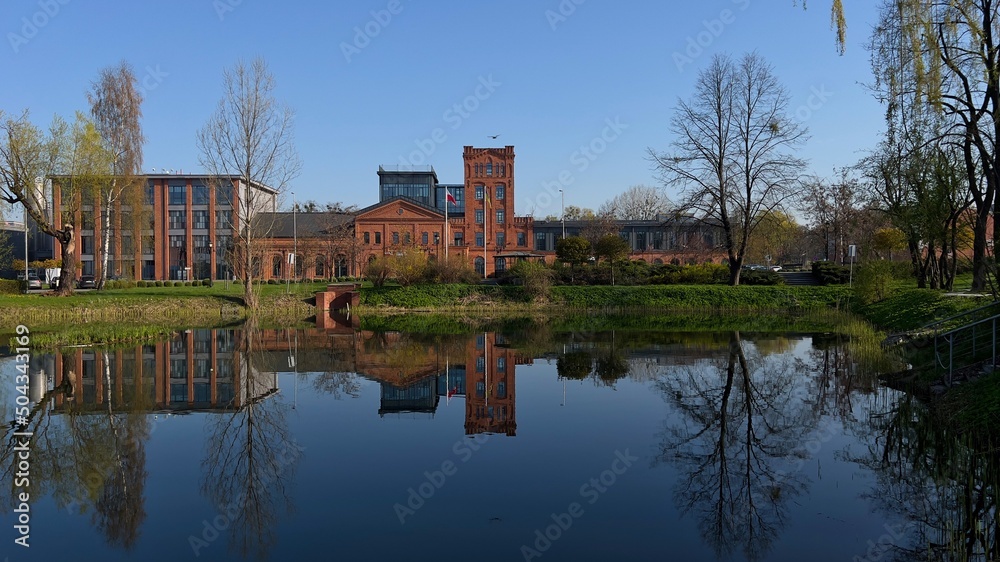 Obraz premium LUSTRZANE ODBICIA BUDYNKÓW W WODZIE. ARCHITEKTURA ZREWITALIZOWANYCH BUDYNKÓW. KSIĘŻY MŁYN, MIASTO ŁÓDŹ, POLSKA.