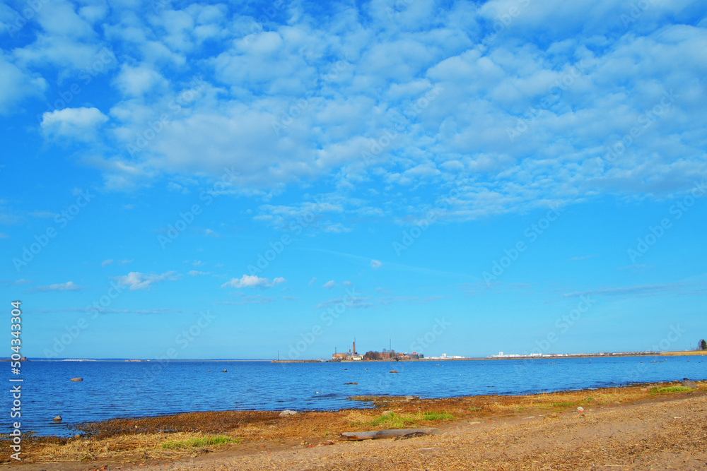 The northern coast of the Gulf of Finland. Sandy beach, blue calm sparkling sea and blue sky. Russia.