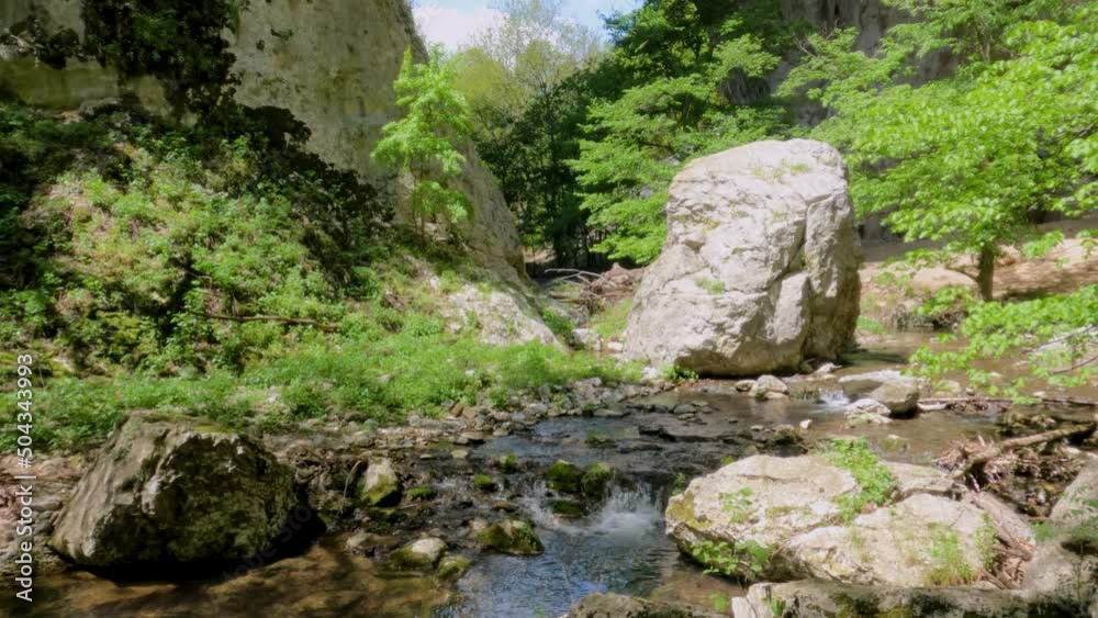Mountain stream flows through rocks near imposing natural stone arches, Vratna River Canyon, eastern Serbia. Geomorphological natural monument. Amazing nature landscape. Spring day. 4K video footage. Mountain stream flows through rocks near imposing natural stone arches, Vratna River Canyon, eastern Serbia. Geomorphological natural monument. Amazing nature landscape. Spring day. 4K video footage.