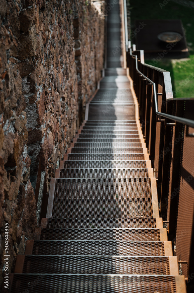 Viele Treppenstufen an einer Mauer entlang, mit Geländer. mit Perspektive von Schärfe im Vordergrund zur Unschärfe