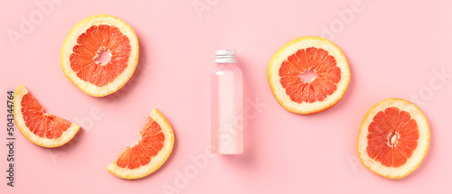 Vitamin c citrus lotion bottle with slices of grapefruit on pink background. SPA body treatment concept.