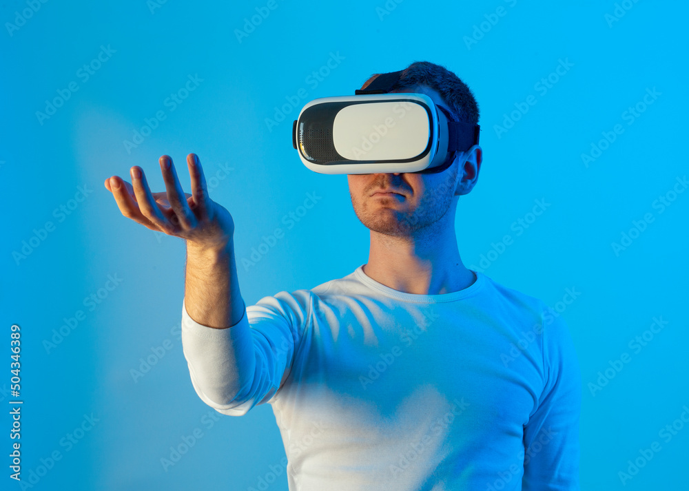 Modern young man experiencing virtual reality glasses in futuristic neon illuminated studio Modern young man experiencing virtual reality glasses in futuristic neon illuminated studio