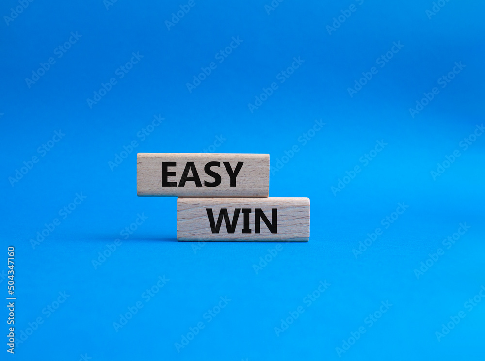 Easy win symbol. Wooden blocks with words 'Easy win'. Beautiful blue background. Business and 'Easy win' concept. Copy space. Easy win symbol. Wooden blocks with words 'Easy win'. Beautiful blue background. Business and 'Easy win' concept. Copy space.