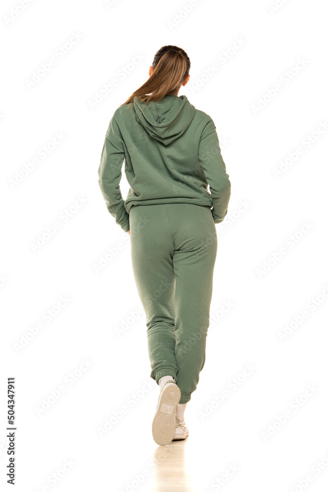 Rear view of a young woman in a green tracksuit posing to a white background in the studio. Rear view of a young woman in a green tracksuit posing to a white background in the studio.
