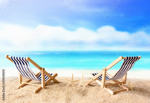 Vacation holidays background concept - two beach lounge chairs on summer beach.