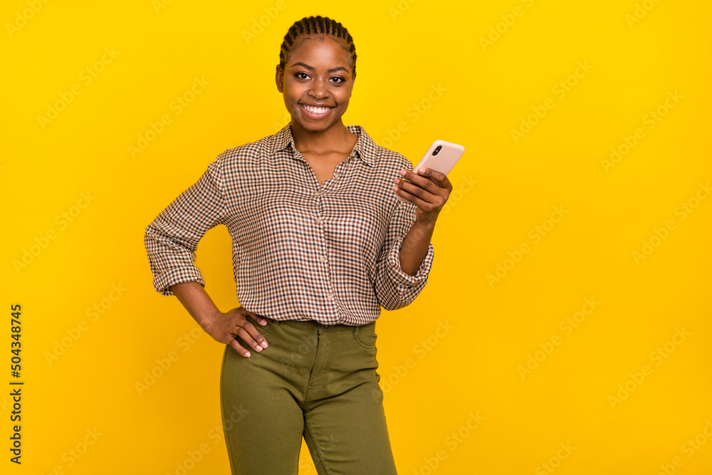Photo of confident pretty lady dressed checkered shirt typing modern device empty space isolated yellow color background Photo of confident pretty lady dressed checkered shirt typing modern device empty space isolated yellow color background