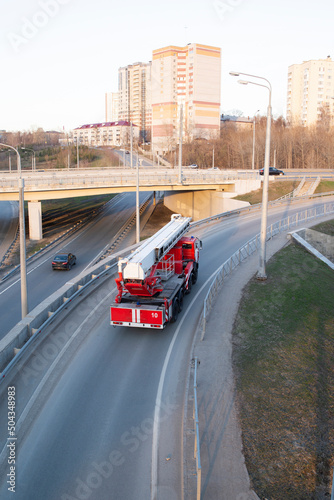 a red fire truck rides on an asphalt road in the city