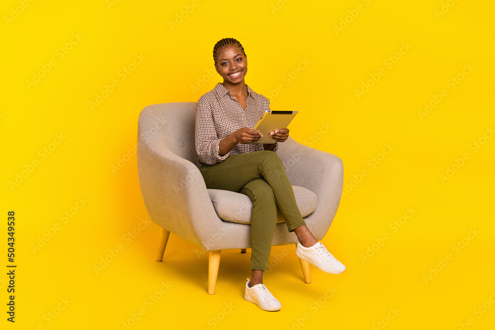 Photo of funny adorable lady dressed checkered shirt sitting chair typing modern gadget isolated yellow color background Photo of funny adorable lady dressed checkered shirt sitting chair typing modern gadget isolated yellow color background