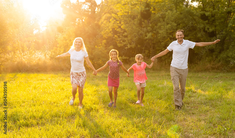 Obraz premium Happy family walking in field and looking at sunset