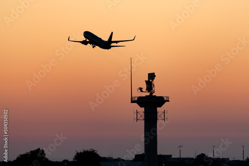 Silhouette of a passenger airplane taking off at sunset.