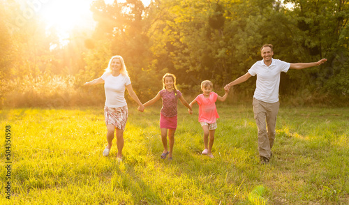 Happy family walking in field and looking at sunset