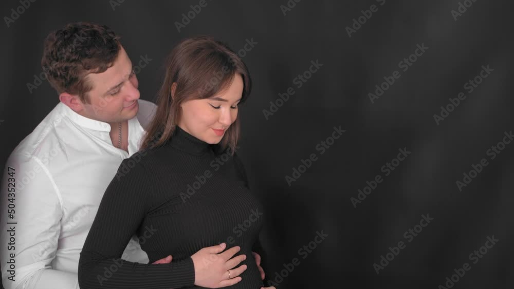 Pregnant young woman with husband expecting a baby. The young family is waiting for replenishment. Happy pregnant woman with big belly resting at home. Young expectant mother caresses her belly. Pregnant young woman with husband expecting a baby. The young family is waiting for replenishment. Happy pregnant woman with big belly resting at home. Young expectant mother caresses her belly.