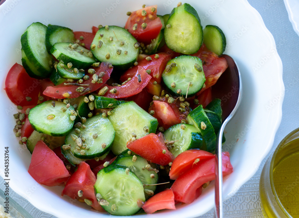 Sliced tomatoes and cucumbers in a plate for morning meal. Top view of traditional Turkish breakfast ingredients with thyme and olive oil. Summer vegan food. Sliced tomatoes and cucumbers in a plate for morning meal. Top view of traditional Turkish breakfast ingredients with thyme and olive oil. Summer vegan food.