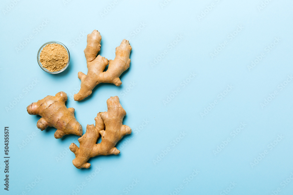 Fototapeta premium Finely dry Ginger powder in bowl with green leaves isolated on colored background. top view flat lay