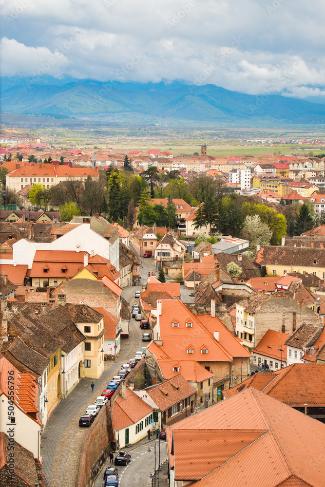Aerial cityscape of historic Sibiu city in Transilvania, Romania, and cloudy Carpathian mountains
