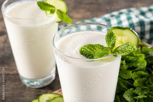 Ayran drink with mint and cucumber in glass on wooden table