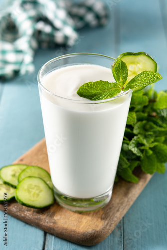 Ayran drink with mint and cucumber in glass on blue wooden table