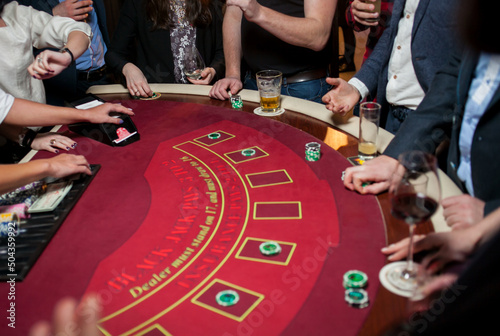 People play poker roulette at the table. Friends playing in the casino. A group of young people at a roulette table with a tape measure. Table for gambling in a luxury casino. Gambling.Casino roulette