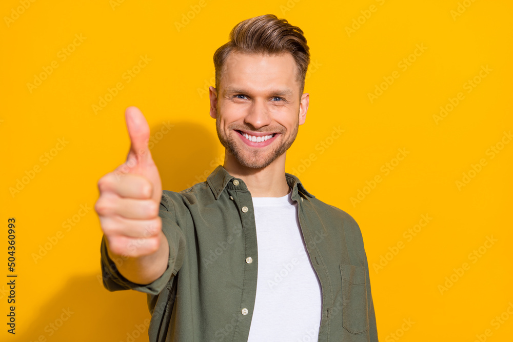 Portrait of attractive cheerful content guy giving thmbup ad advert isolated over bright yellow color background Portrait of attractive cheerful content guy giving thmbup ad advert isolated over bright yellow color background