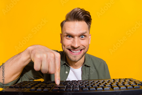 Portrait of attractive cheerful crazy guy pressing button studying gambling having fun isolated over bright yellow color background photo