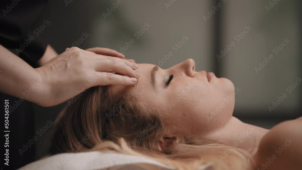 chiropractor is curing headache by massage, physician is massaging forehead of young female client chiropractor is curing headache by massage, physician is massaging forehead of young female client