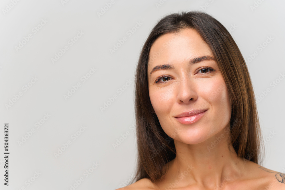 Tender and young. Portrait view of the multiracial brunette woman with naked shoulders and nude makeup posing with pleasure face at the studio with white background. Beauty Tender and young. Portrait view of the multiracial brunette woman with naked shoulders and nude makeup posing with pleasure face at the studio with white background. Beauty