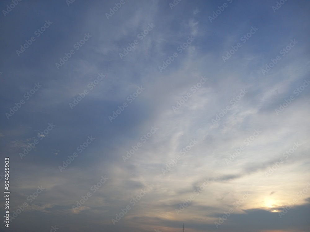 light blue sky with little cirrus cloud and shiny sun set at bottom right side