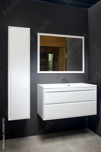 Stoneware countertop bathroom with dark tired beton wall stoneware tiled floor. White industrial flat loft bathroom with modern countertop basin, square mirror and wooden PVC cupboard.