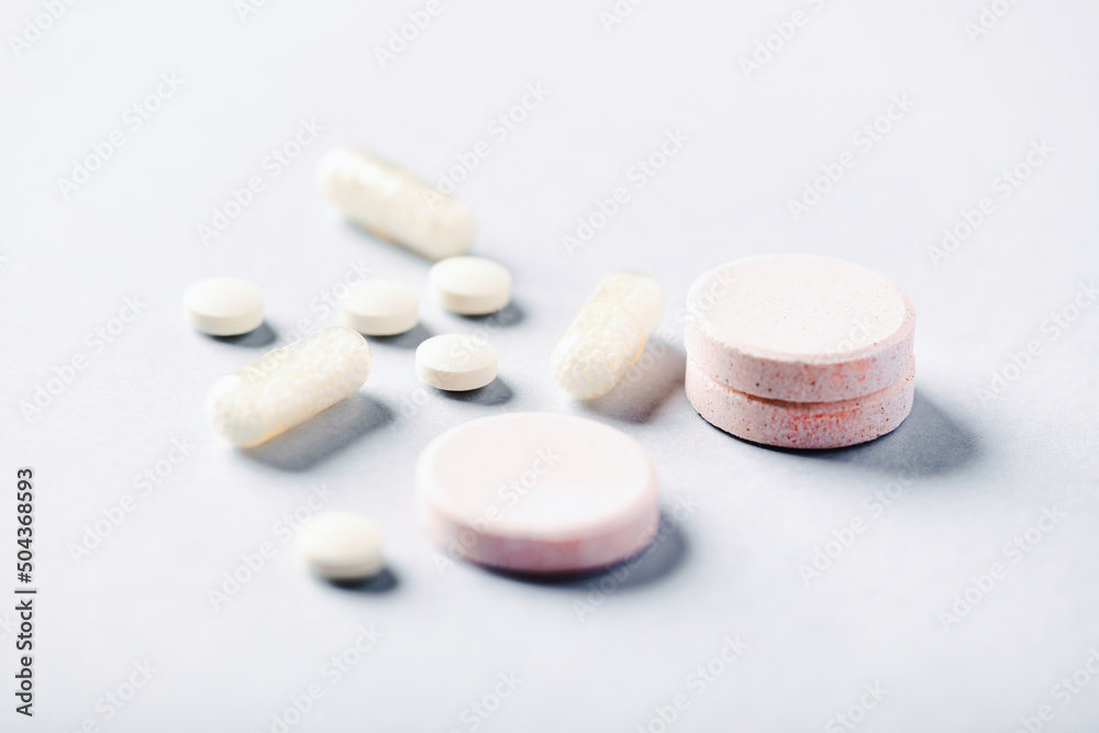 Collagen effervescent Tablets and Vitamin C tablets and capsules. Supplements to support collagen production. Bright paper background. Soft focus. Close up. Collagen effervescent Tablets and Vitamin C tablets and capsules. Supplements to support collagen production. Bright paper background. Soft focus. Close up.