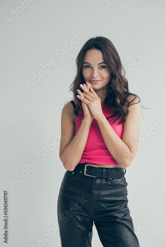 Young woman smiles and poses against grey background.