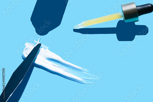Pipette with dose of fluid hyaluronic acid on blue background. cosmetic concept. flat lay.