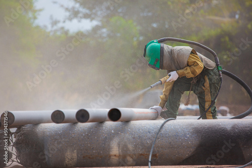 Fotografia Male worker Sand blasting process cleaning pipeline surface