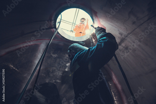 Welding arc argon worker male repaired metal is welding sparks industrial construction tank part manhole stainless oil inside confined spaces photo