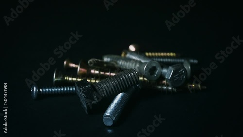 Metal fasteners rotate on a dark background
