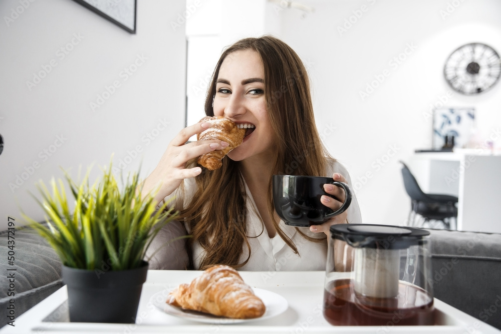 A Young Girl take Breakfast in Bed. French Croissants With Tea on a Tray.