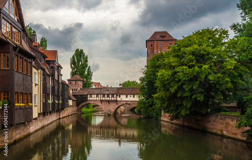 The former residence of Nuremberg’s official executioner on the arch bridge over the river Pegnitz with the executioner’s tower (Henkerturm) on a cloudy day. On the right hand stands the water tower. photo