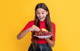 amazed girl hold fresh fruit plate on yellow background