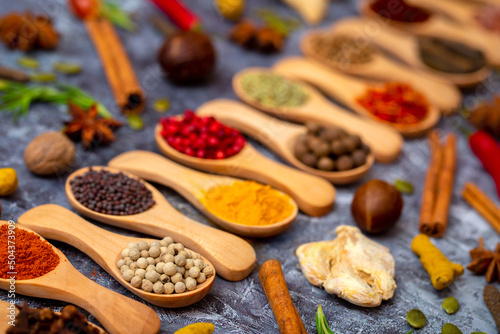 A set of spices on a gray background. Variety of spices from India. Food decoration design. Various spices, peppers and herbs close-up top view. Set of peppers, salt, herbs and spices for cooking.