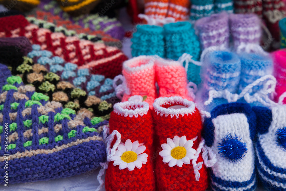 Knitted baby booties in other knitted things on the background.