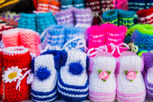 Knitted baby booties in other knitted things on the background. © Сергей Жмурчак