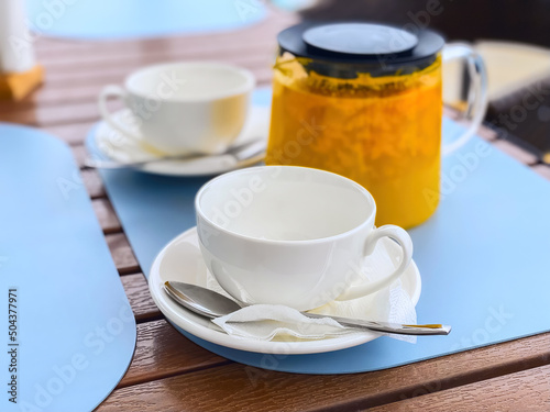 Sea buckthorn tea in a teapot and two white cups on a table in an outdoor restaurant