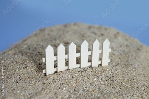 Barrière miniature blanche en bois dans le sable photo