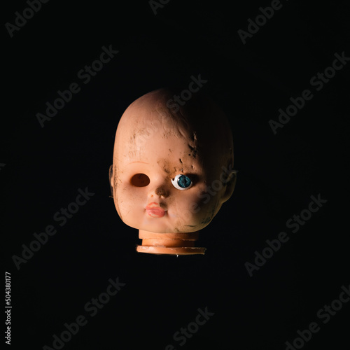 Damaged Dirty Doll head on black background photo