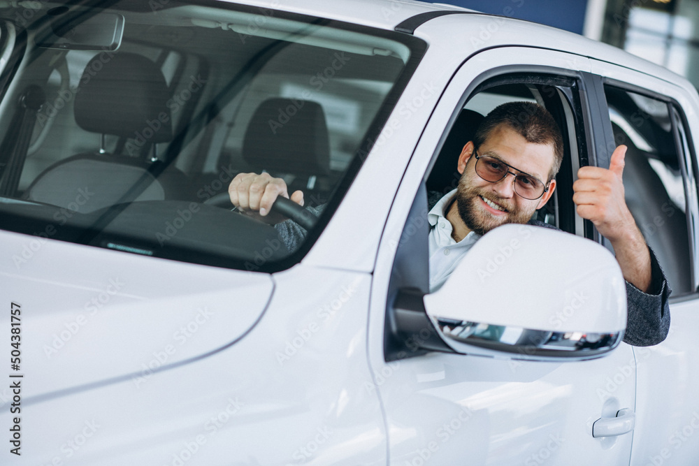 Young man sitting in a new car in a showroom