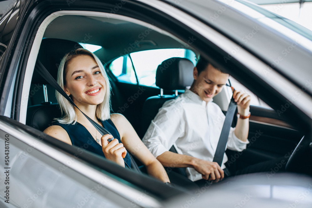 Young couple sitting in a car in a car showroom