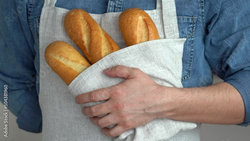 Close up of male hands hold freshly baked french baguette in kitchen linen towel. Bread bakery. Food background photo