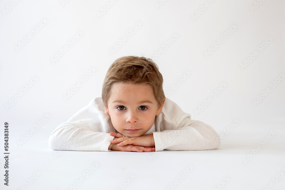 Cute stylish toddler child and older brothers, boys with white shirts on white background, family kids portrait Cute stylish toddler child and older brothers, boys with white shirts on white background, family kids portrait